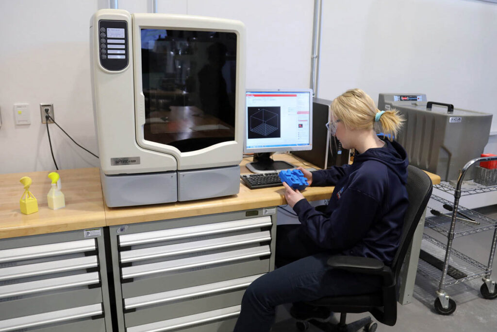 Student operating a 3D printer in a lab