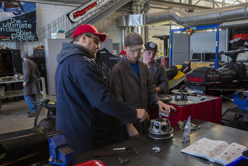 Students and instructor looking at piece of vehicle