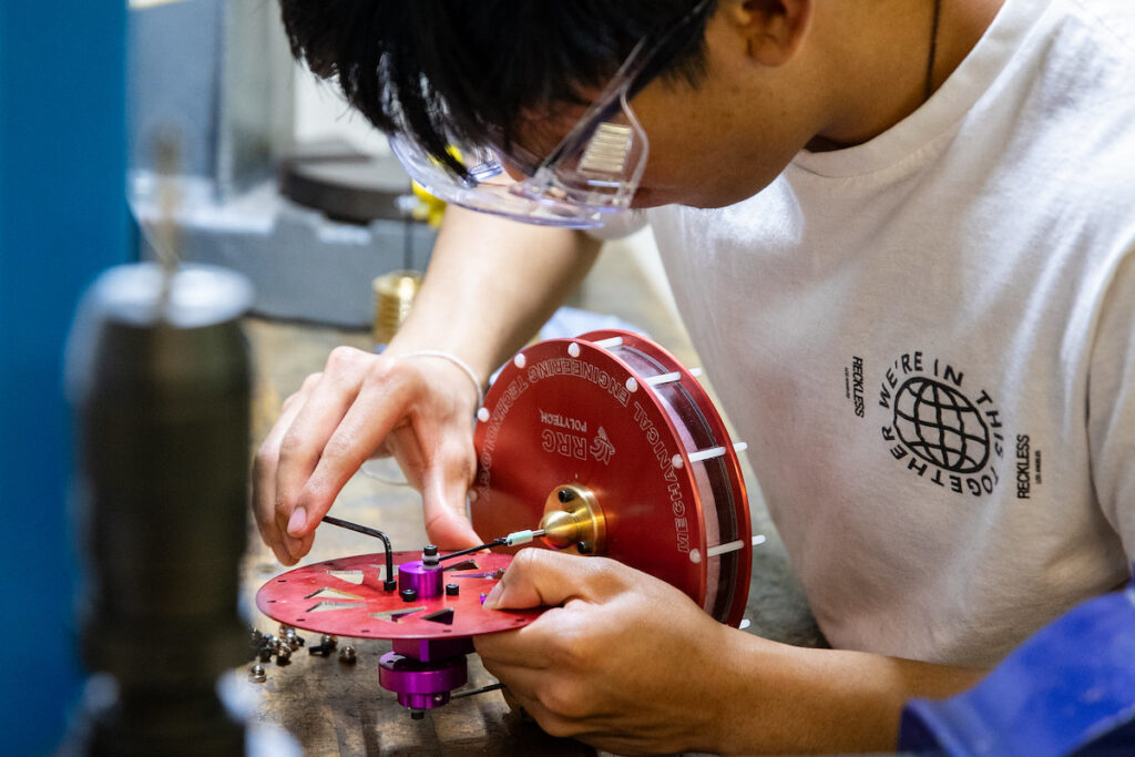 Student assembling an Sterling engine in a shop environment.