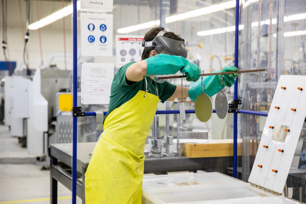 Student wearing personal protection equipment while manipulating engine components in a shop environment.