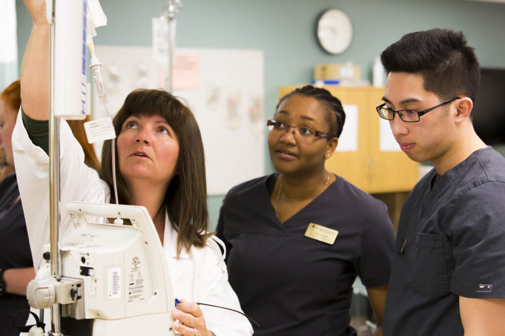 Nursing instructor showing students how to hook up IV bag