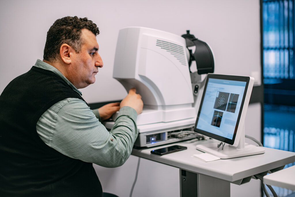 Man working with medical equipment and looking at the results on a computer screen