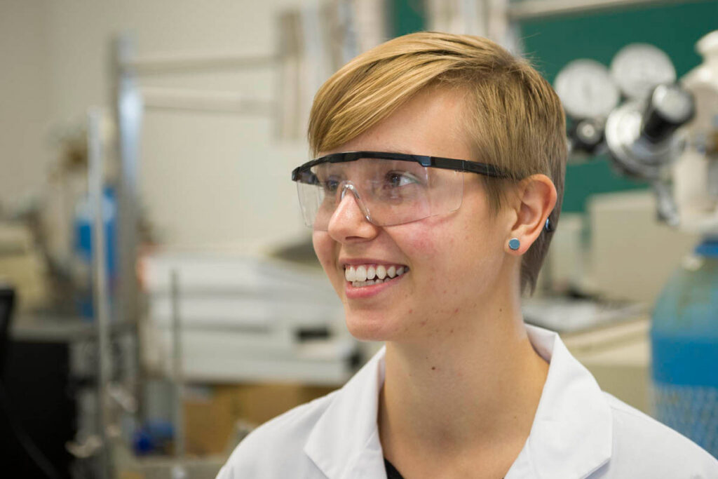 Smiling student wearing safety glasses in a lab 