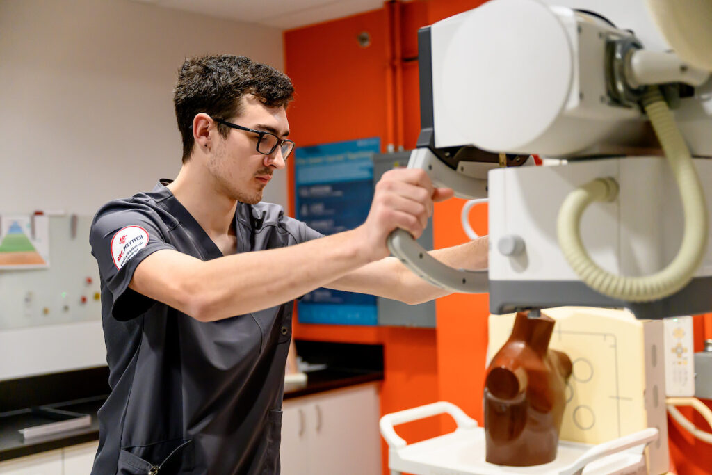 Radiologic technologist student operating imaging equipment in a lab