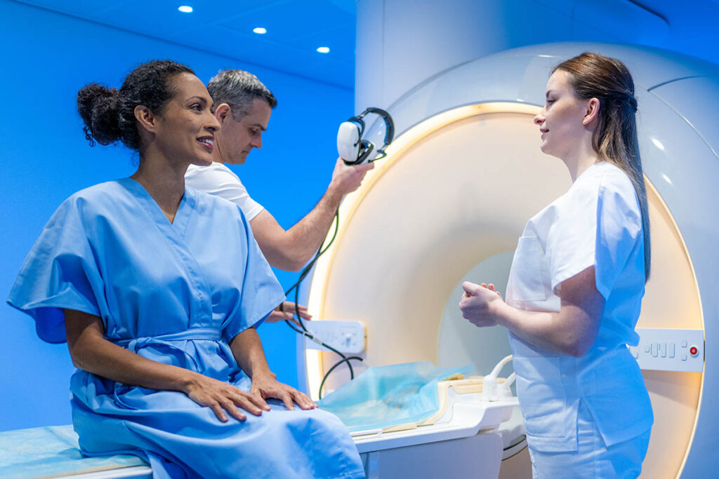 Two MRI technicians talking to patient who is about to get a scan