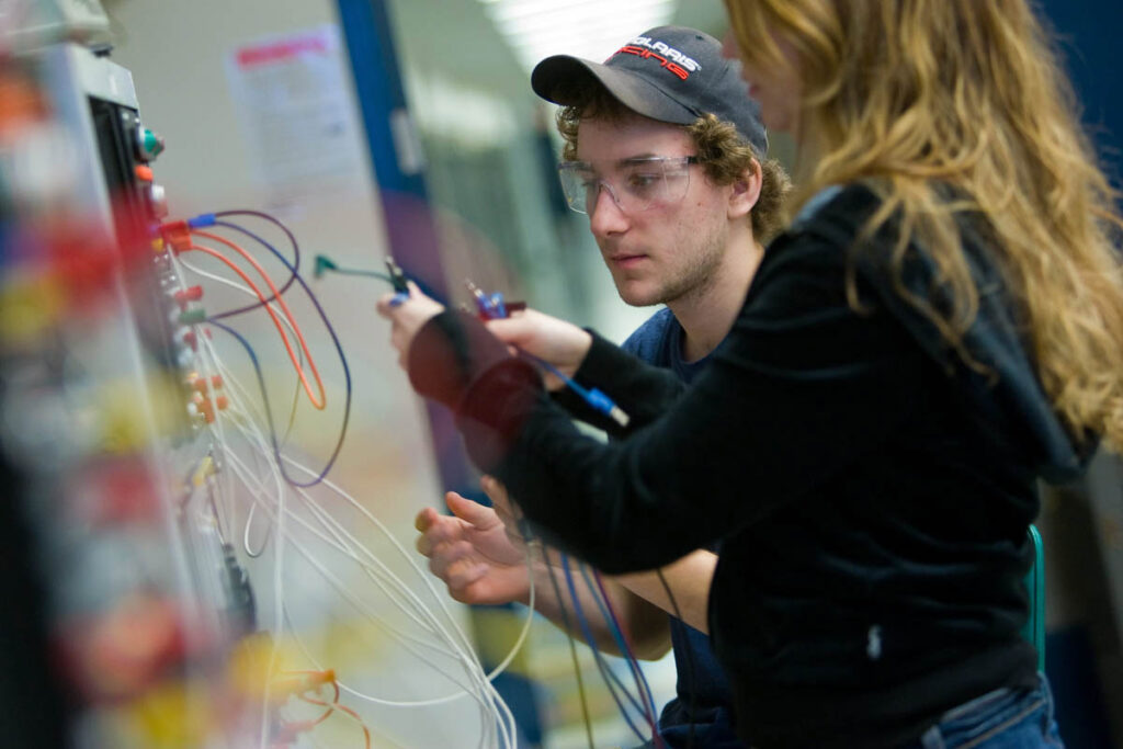 Students plugging cables into networking switches in lab