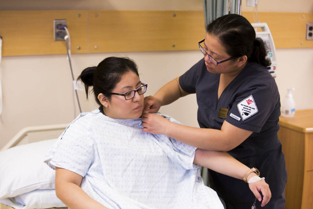 Nursing student assisting patient with gown