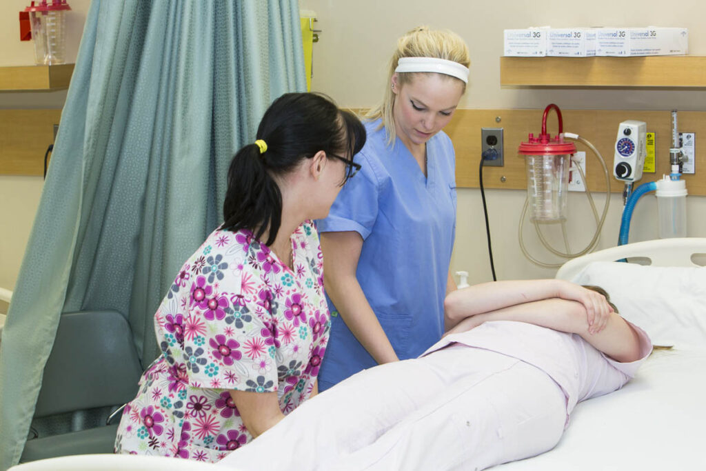Nursing students assisting patient in hospital bed