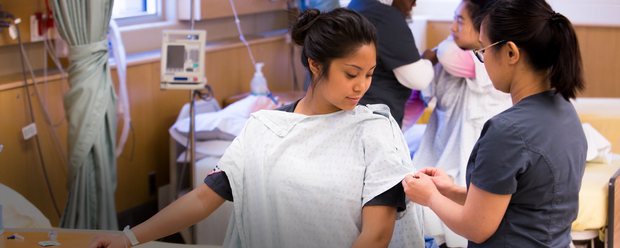 Nursing student assisting patient with gown