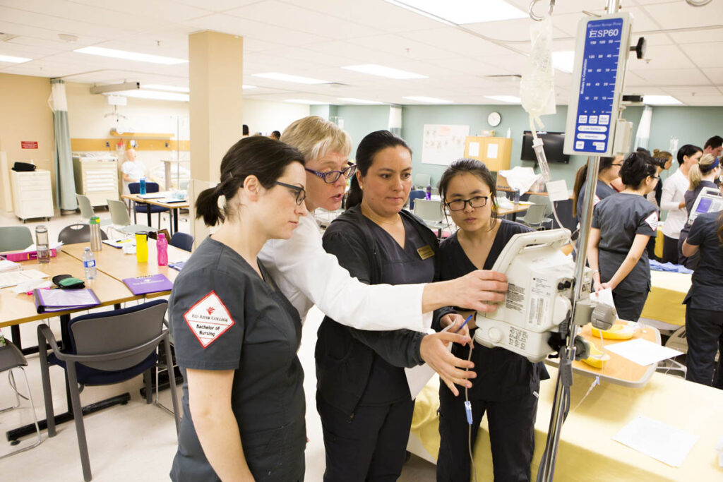 Nursing instructor showing students how to use equipment in a nursing lab