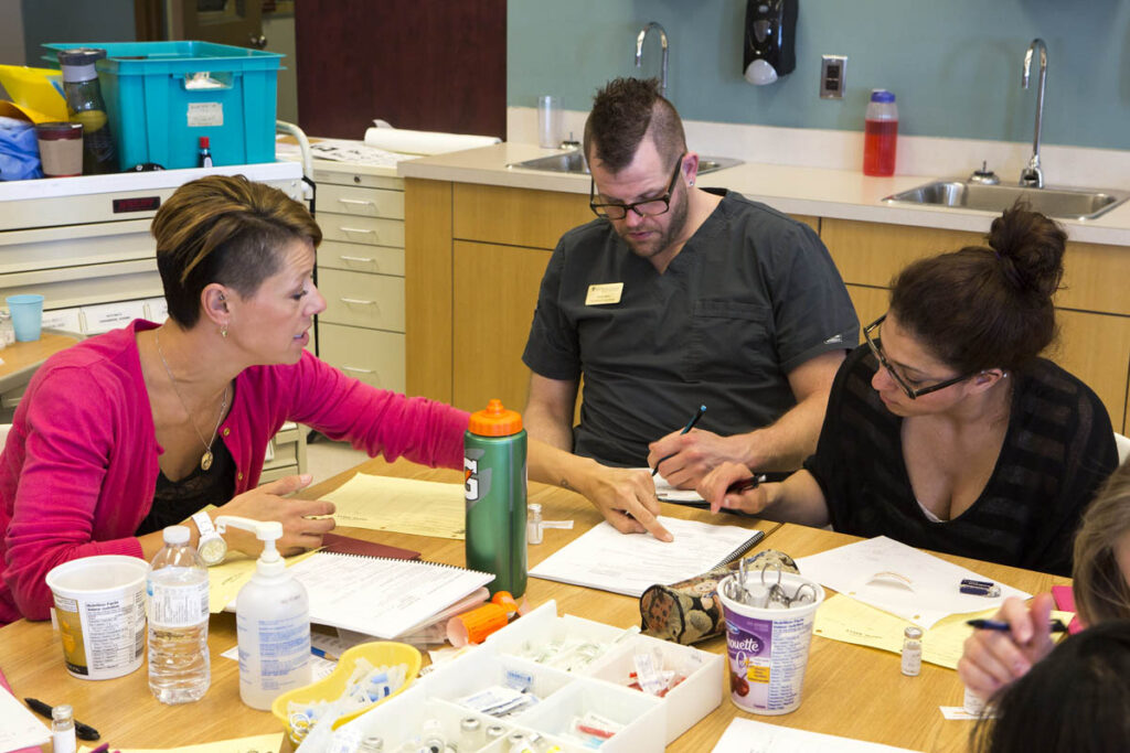 Nursing instructor showing students something in a notebook