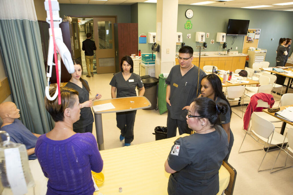 Nursing instructor showing students how to use equipment in a nursing lab