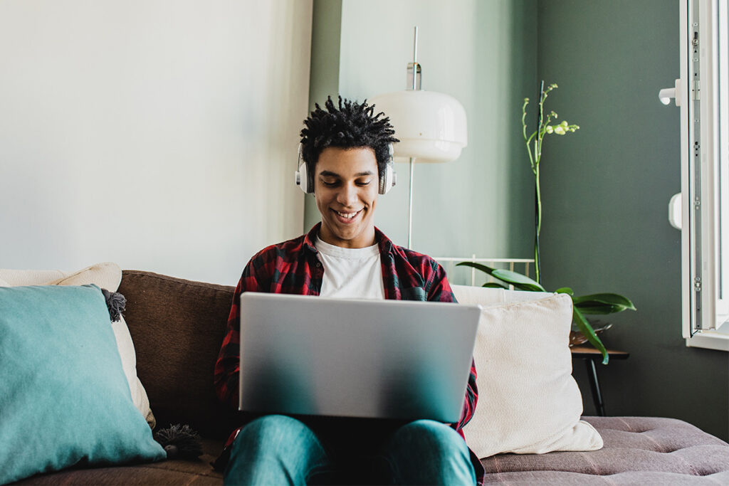 Student sitting on couch with laptop and headphones