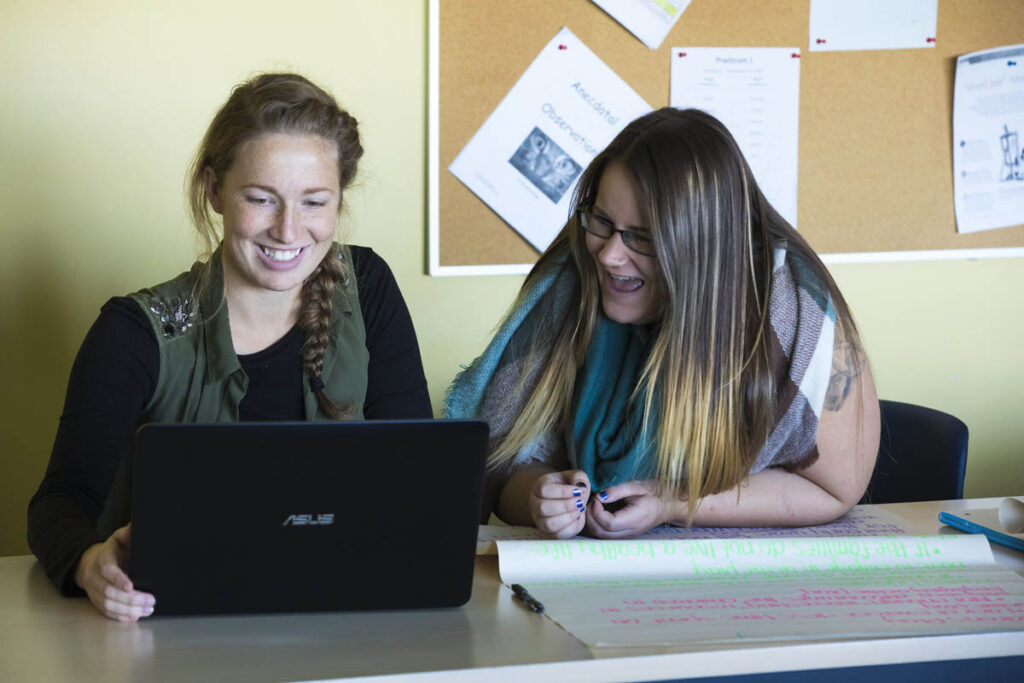 Two students looking at a laptop in class 