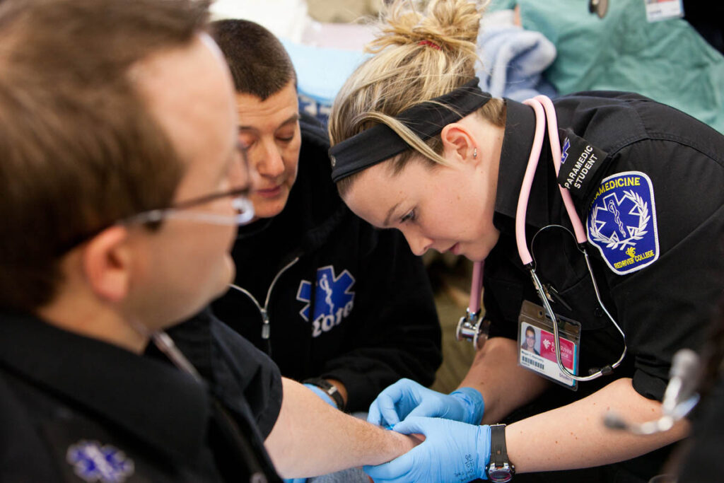 Paramedicine student practicing giving an IV to a patient 
