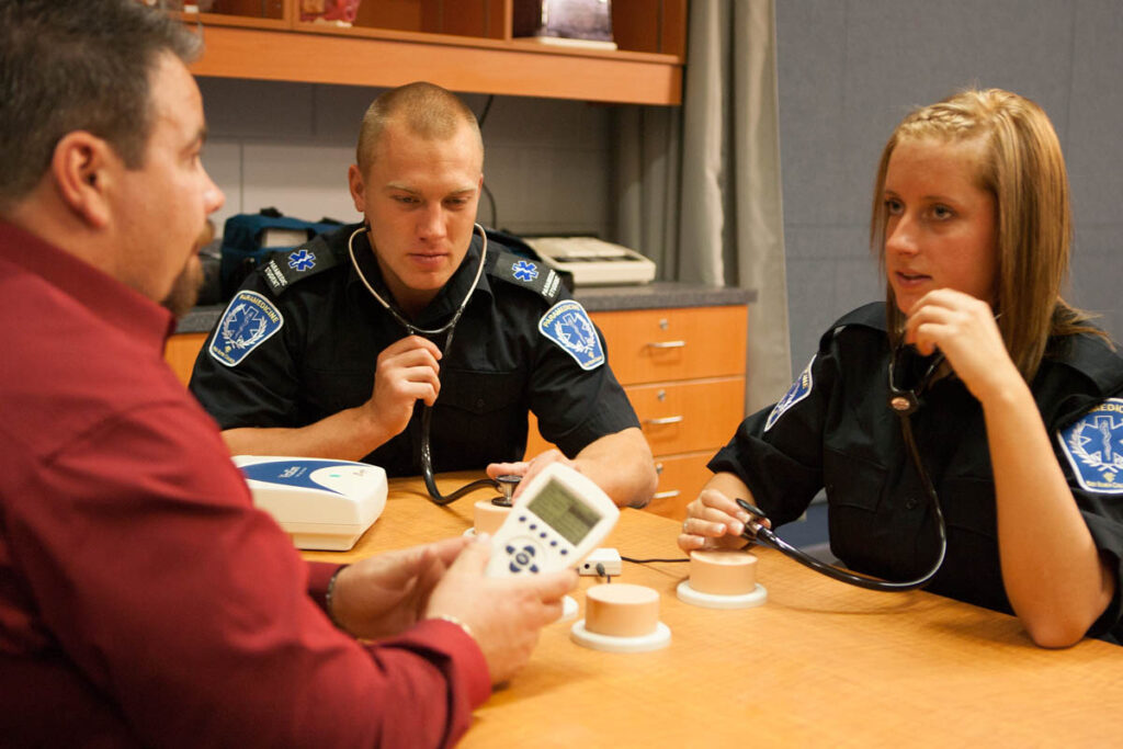 Paramedicine students sitting at a table wearing stethoscopes