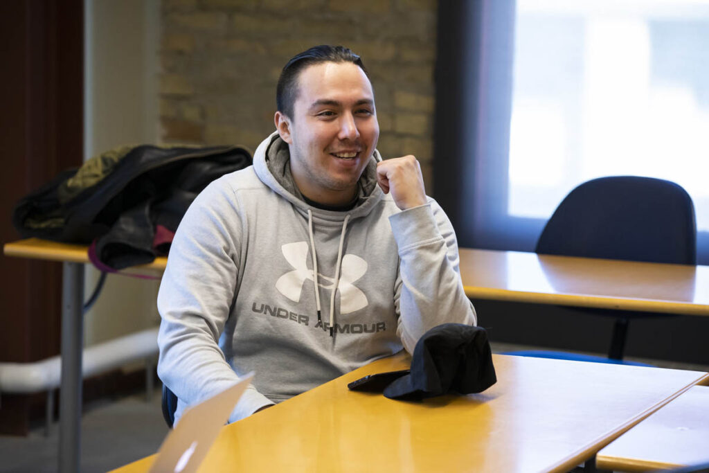 Smiling guy sitting at a table in a classroom