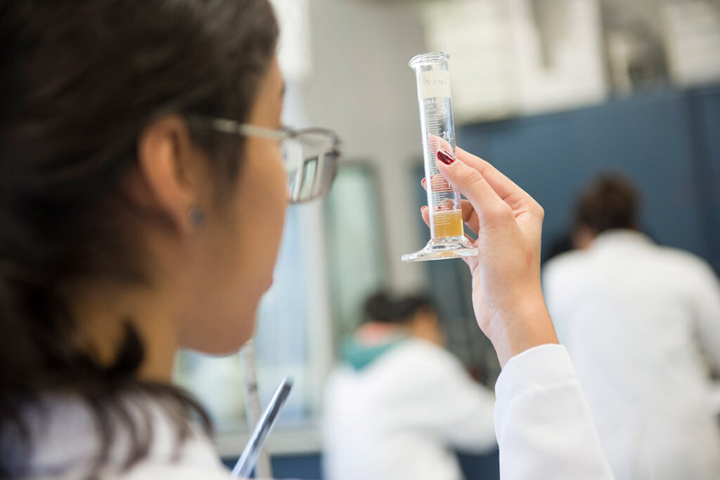 Student examining test tube with yellow liquid