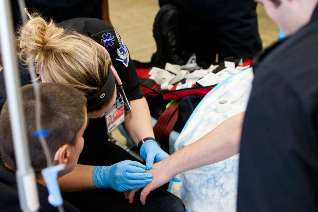 A paramedicine student looking for a vein on a patient to give an IV