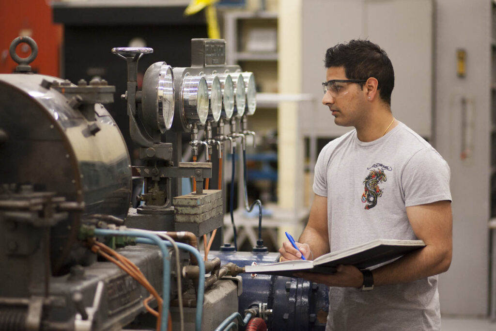 Power engineer looking at gauges and taking notes