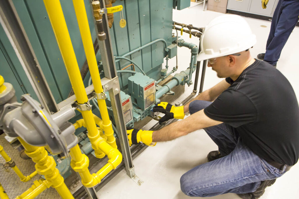 Power engineer in hard hat working with a boiler