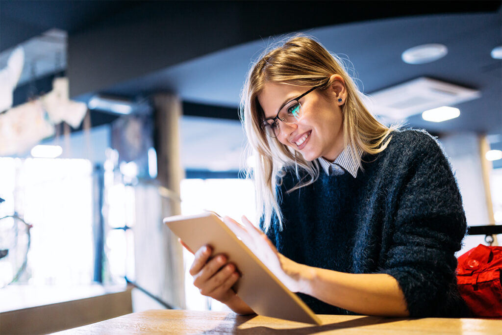 Smiling woman sitting at a table using a tablet