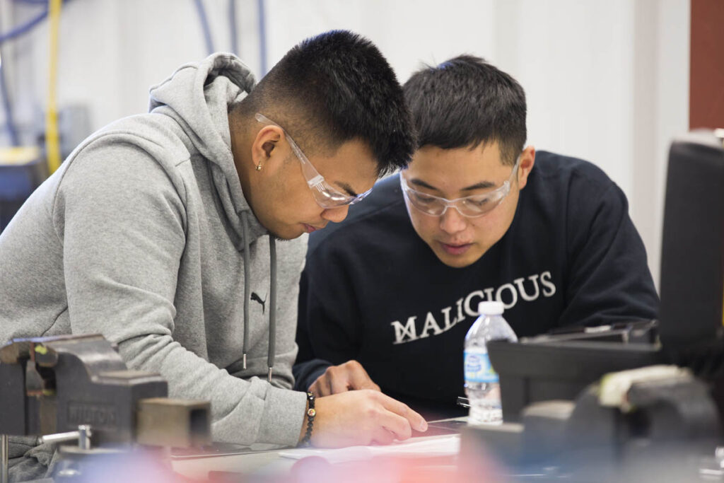 Two students wearing safety glasses and taking notes