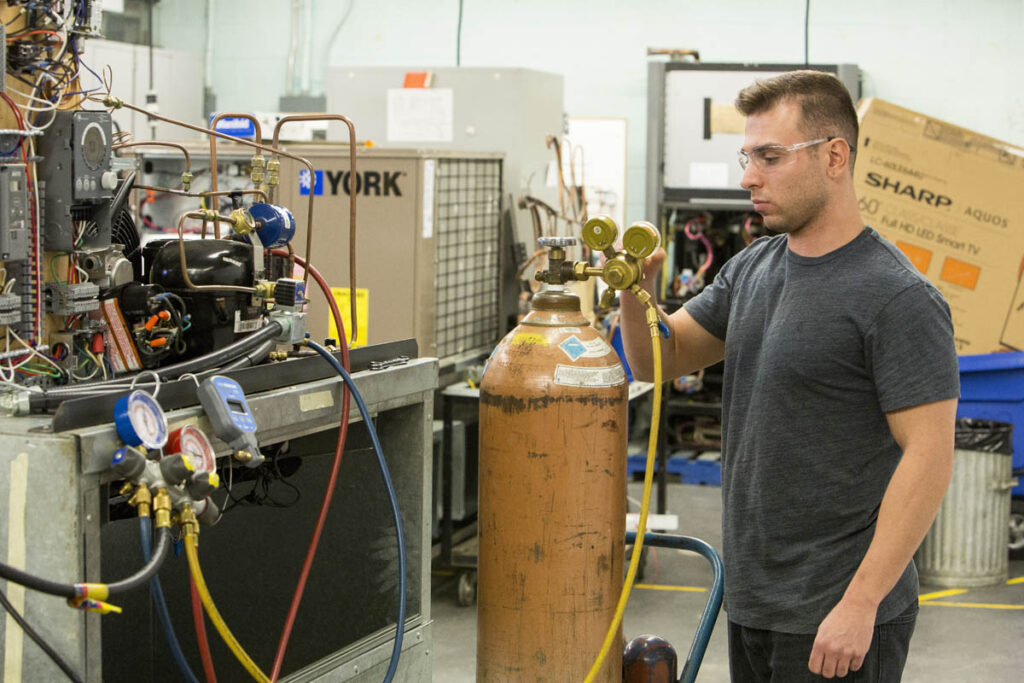 Student looking at pressure gauges on a large tank in a lab