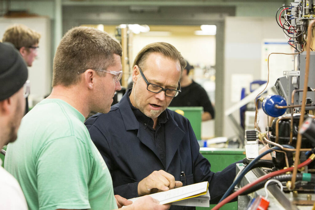 Instructor talking to student in a lab and looking over his notes