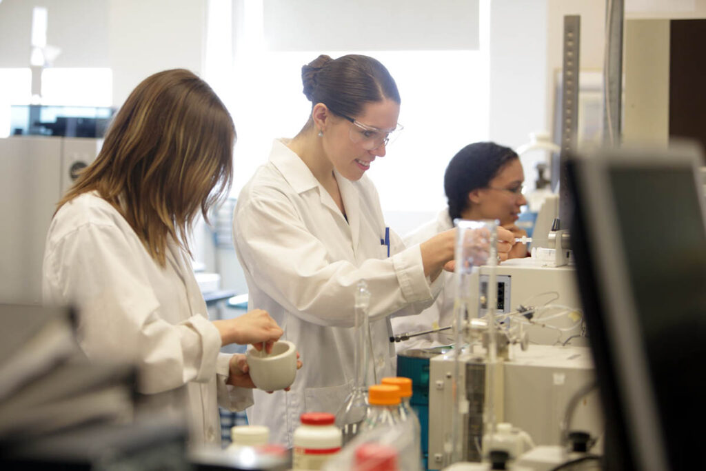 Students wearing white lab coats running a test on something in a science laboratory