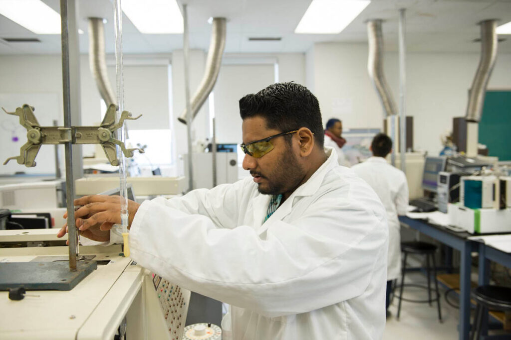 Student wearing a white lab coat working in a science laboratory