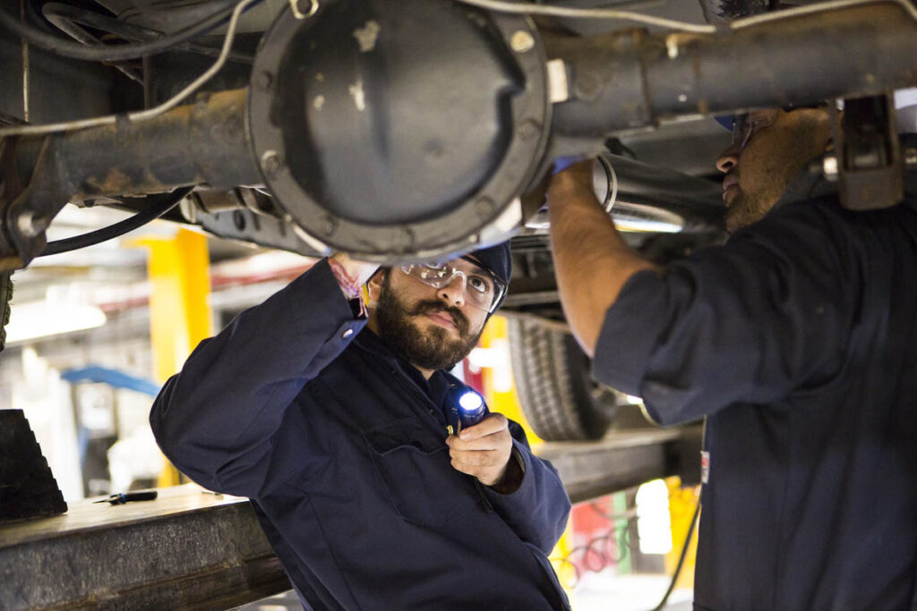 Students hoisting a vehicle up and looking at the axel