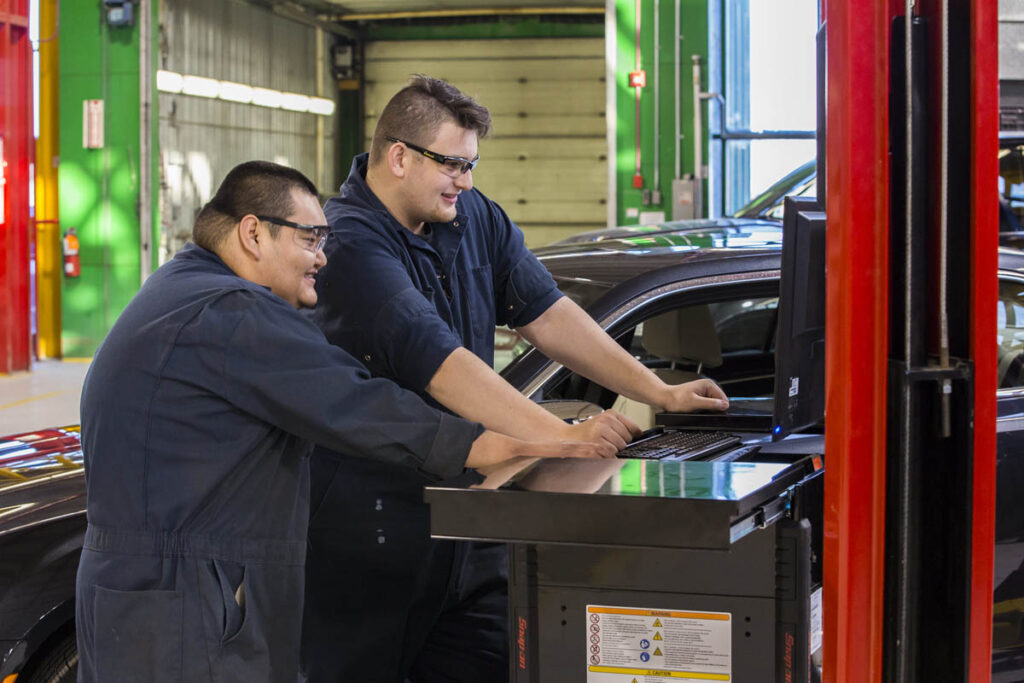 Mechanics using a computer to inspect a vehicle