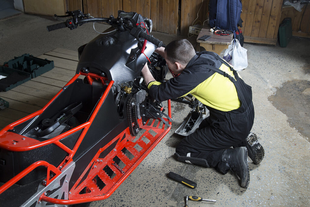 Mechanic fixing a snowmobile