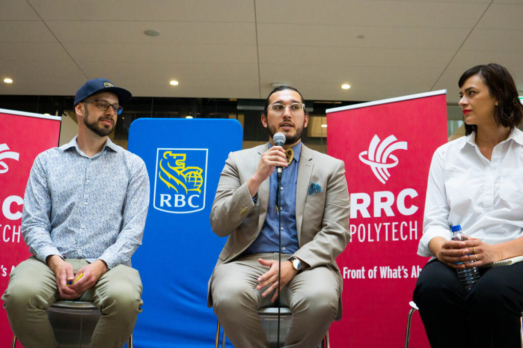 Three panelists on stage talking at an event