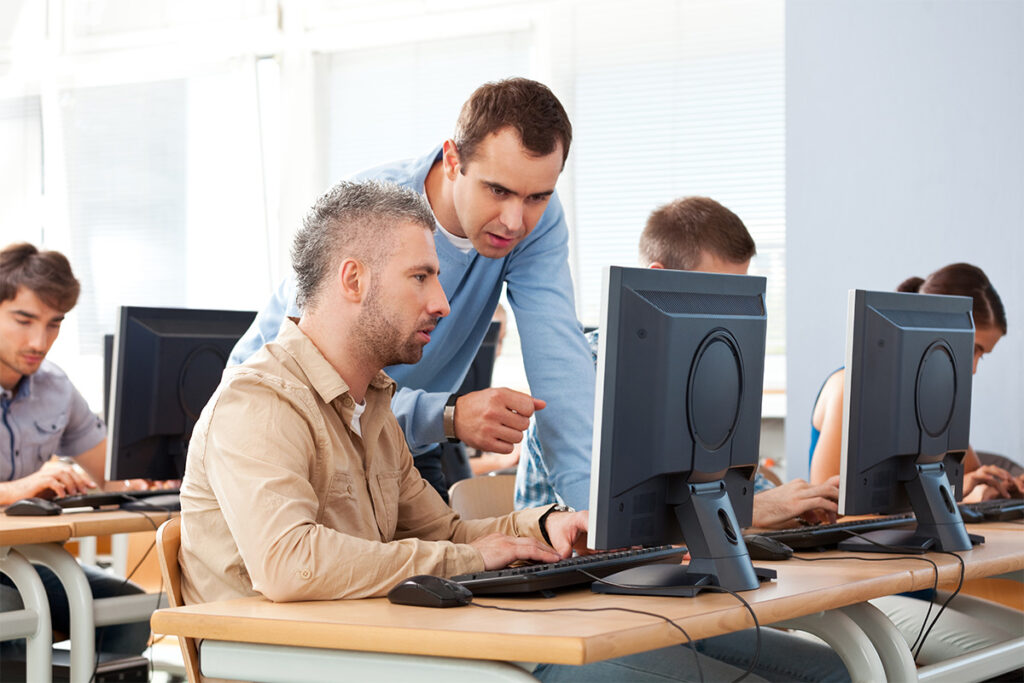 Instructor explaining something to student in a computer lab