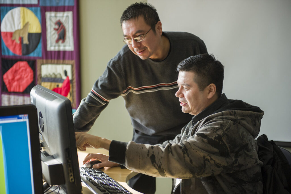 Instructor explaining something to student in a computer lab