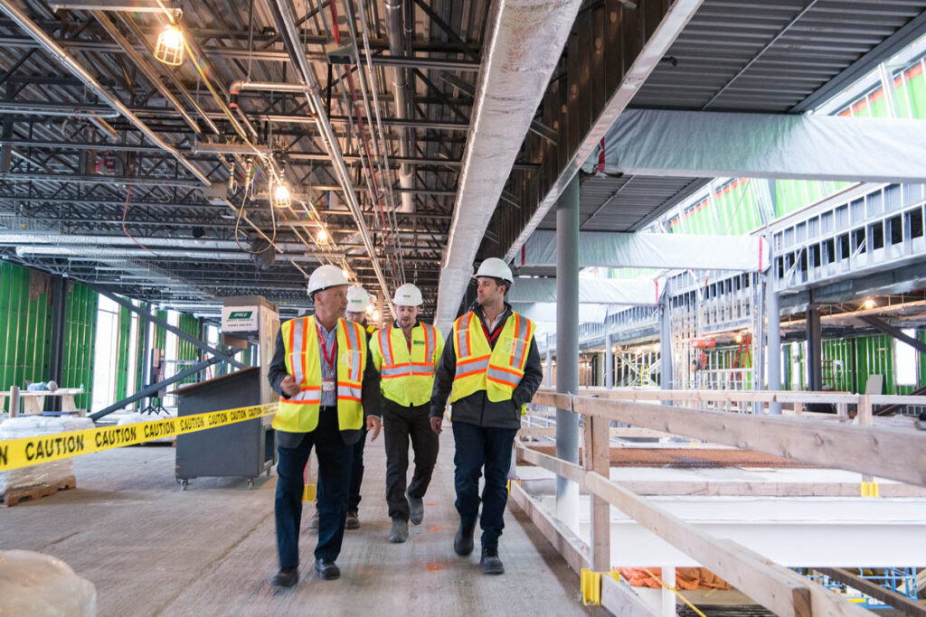 Three engineers in safety vests walking through a construction site