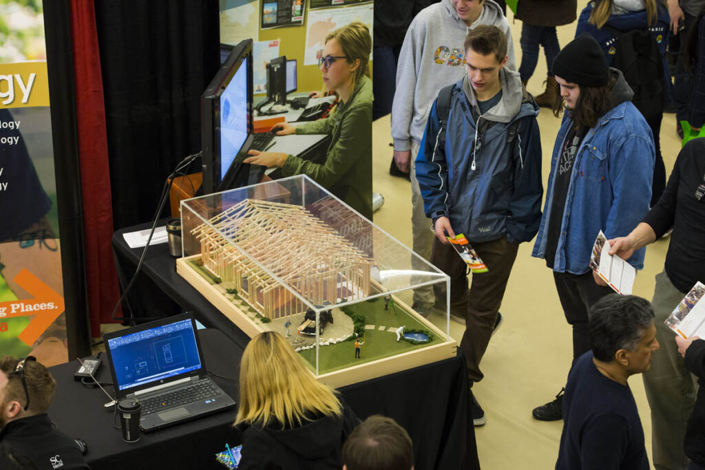 Students looking at model of building at trade show
