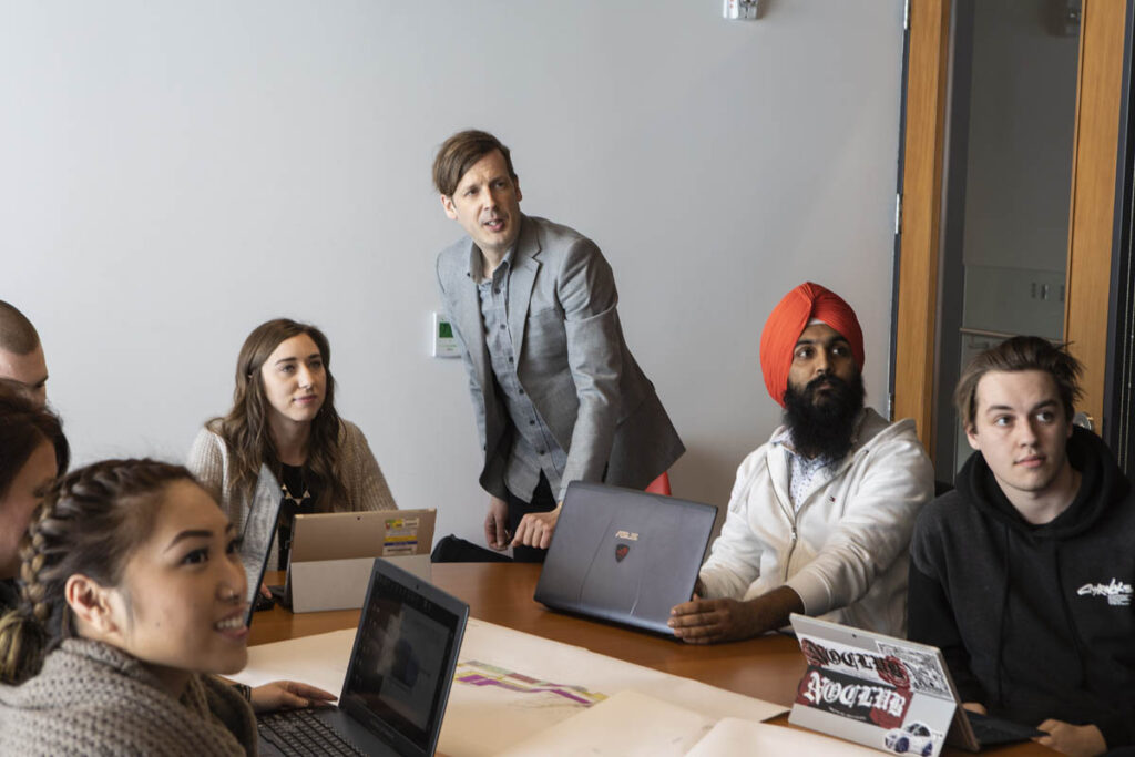 Instructor and students looking at a screen in a boardroom