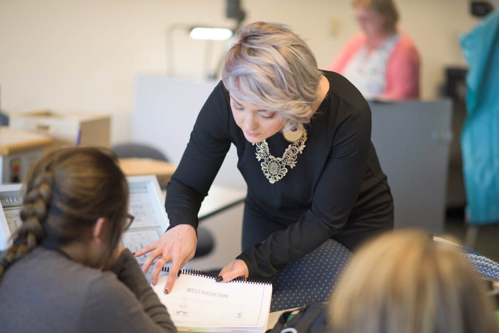 Instructor pointing to some notes while talking to a student in a classroom