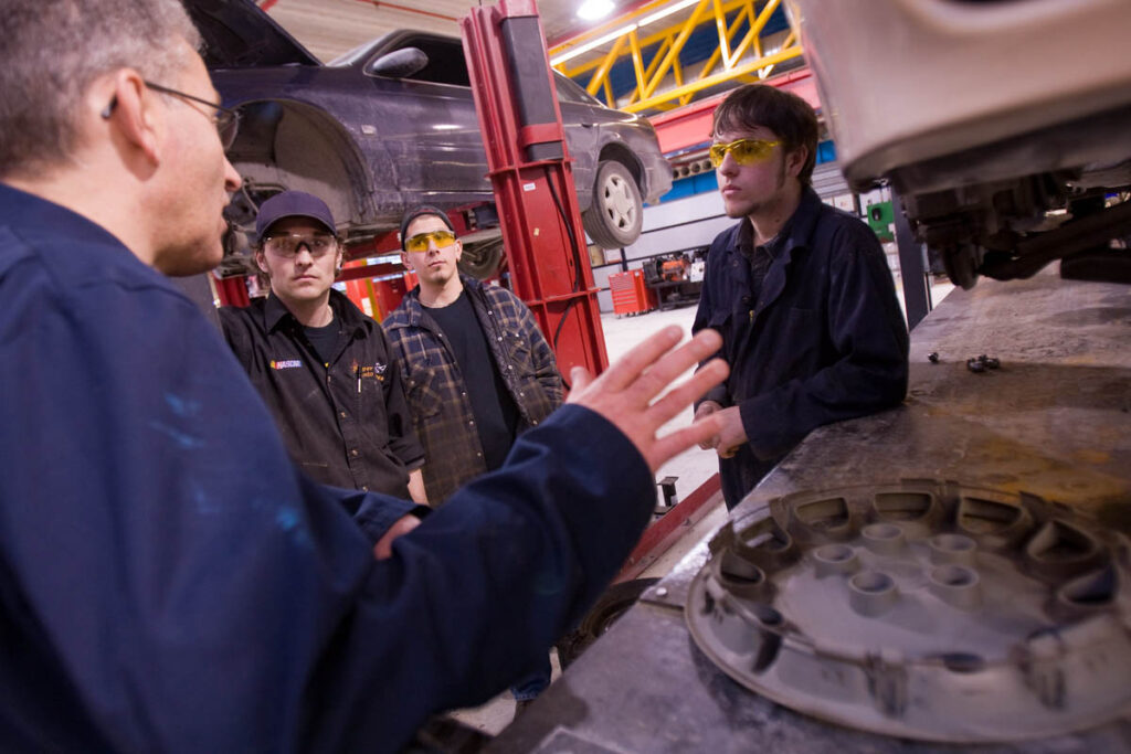 Auto mechanics instructor talking to students in an auto body shop
