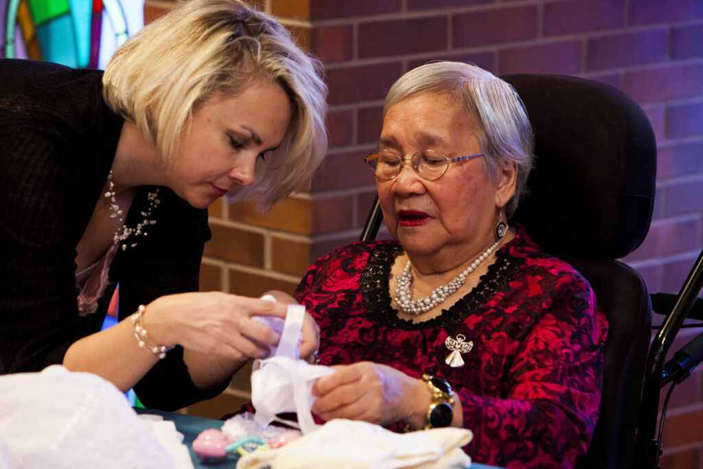 Woman helping elderly lady at a crafting event in a care home