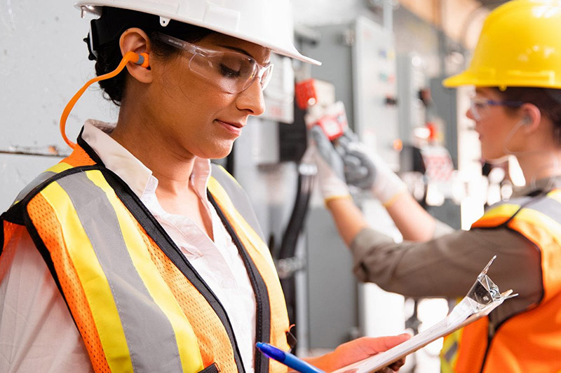 Woman in orange safety vest looking at clipboard