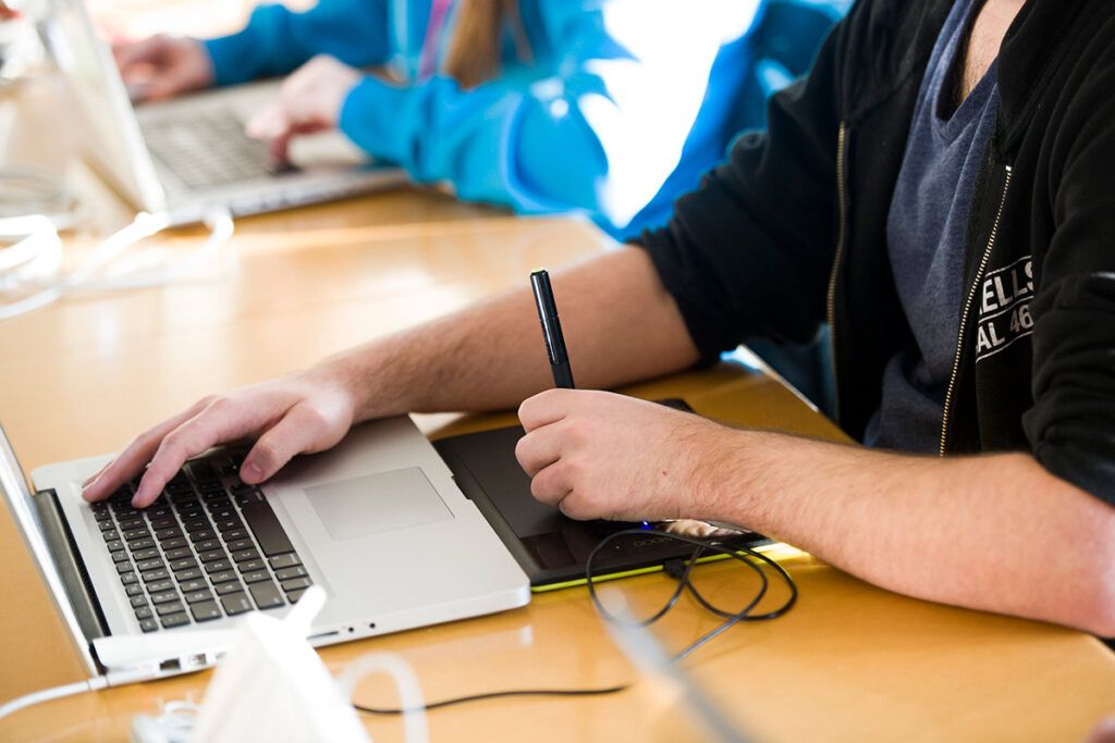 Person using a laptop and drawing on a tablet