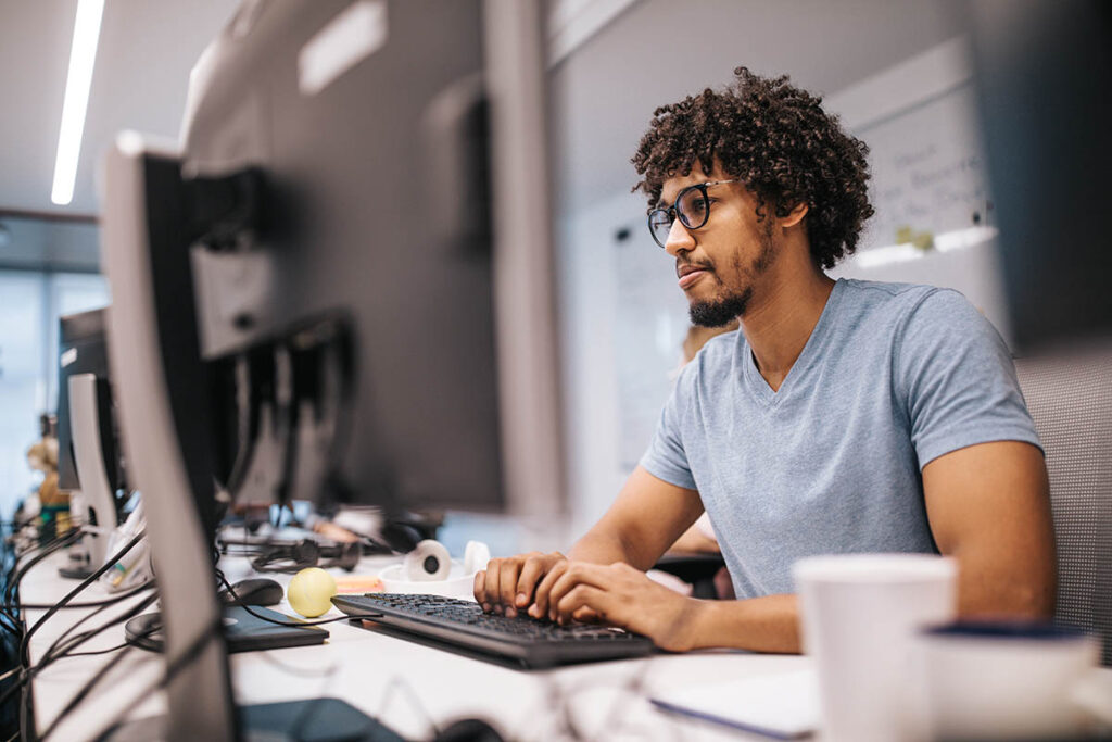 Guy sitting in a computer lab and typing on a keyboard