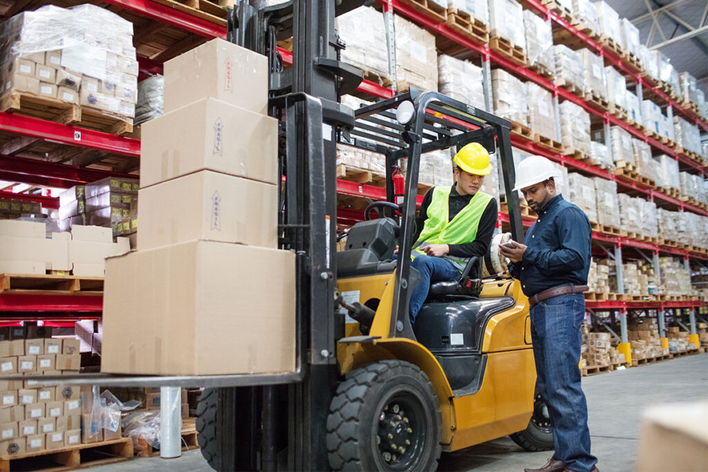 Forklift operator lifting boxes in a warehouse