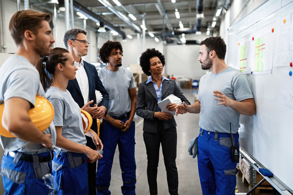 Group of people walking by a whiteboard in a warehouse