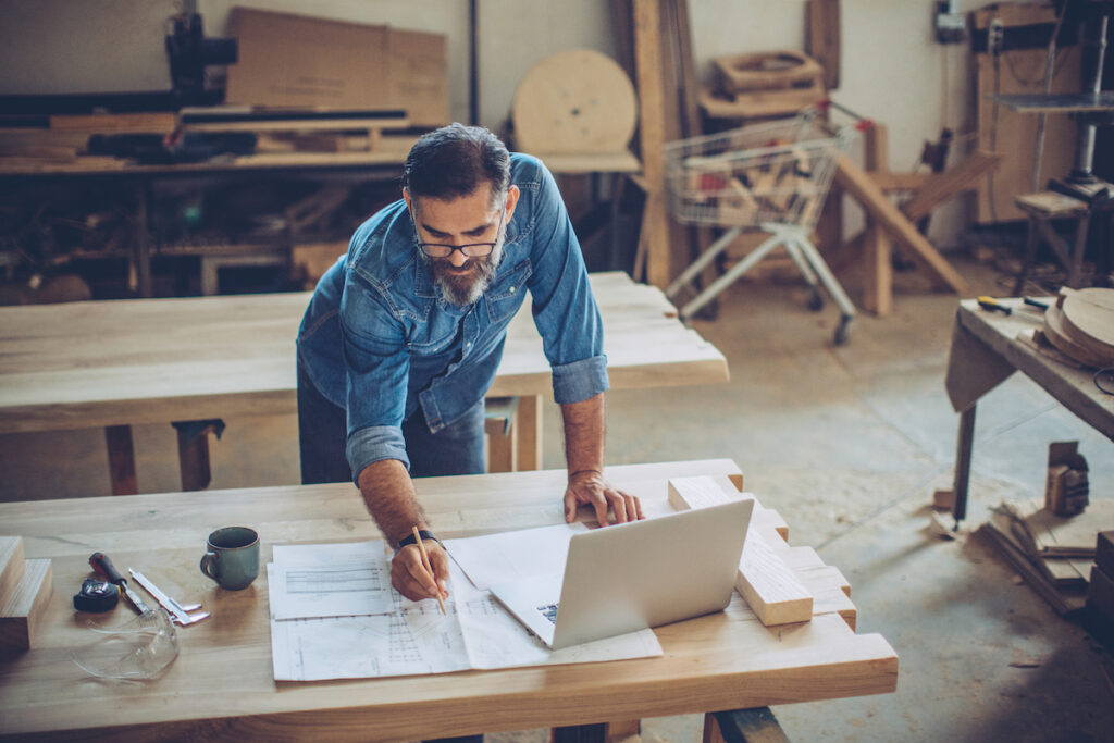 Man in woodshop checking diagrams