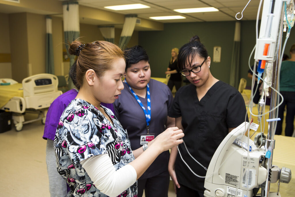Nursing instructor showing students how to operate a medical device